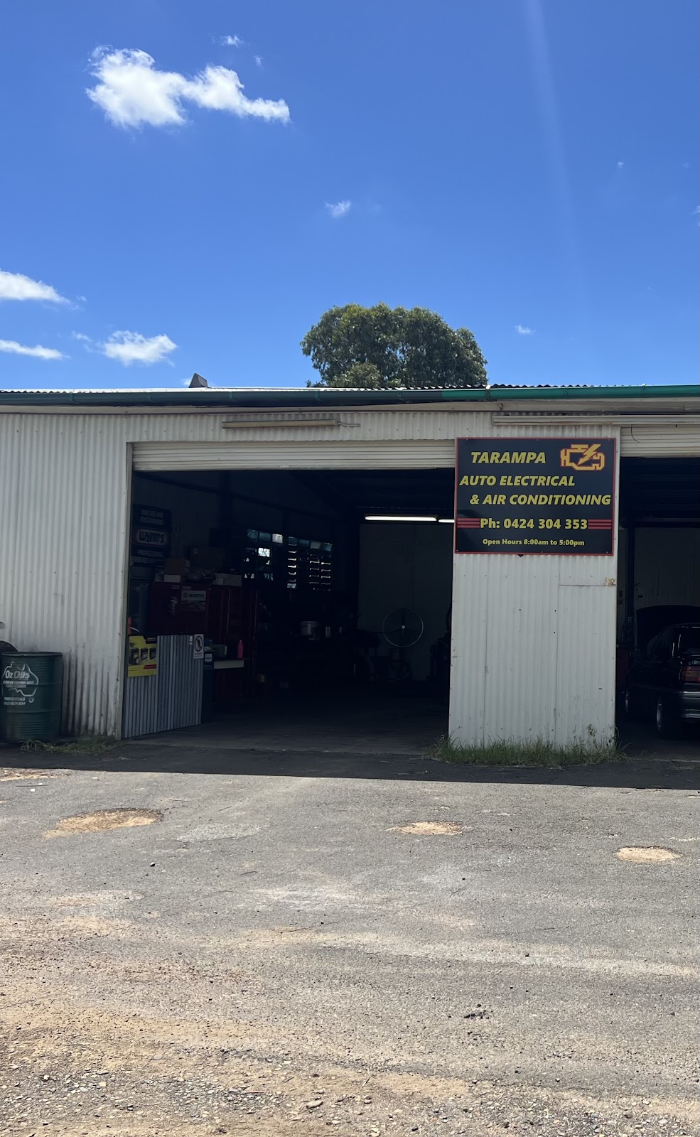 The Tarampa Auto Electrical workshop: a corrugated iron shed with its roller door open and the black and yellow sign