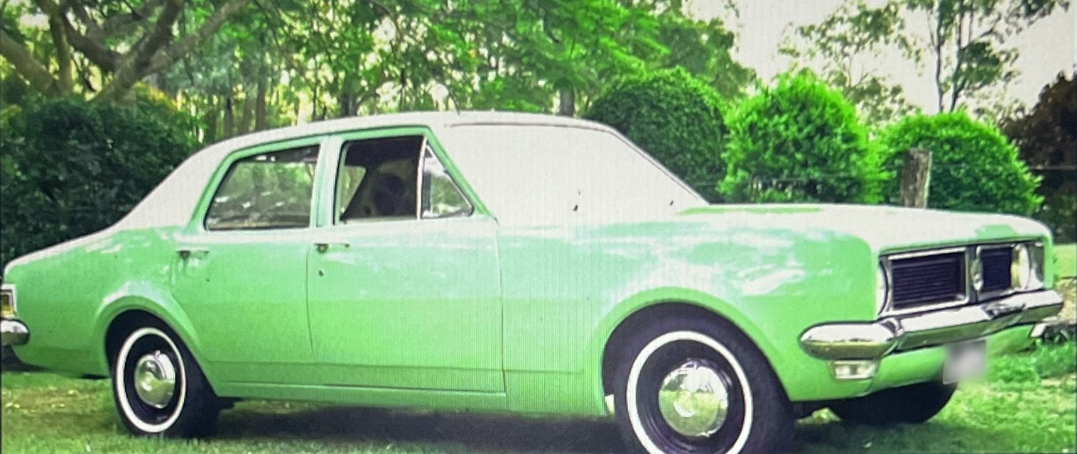 A pale green classic Holden sedan parked on the grass, from Tarampa Auto Electrical's own business card
